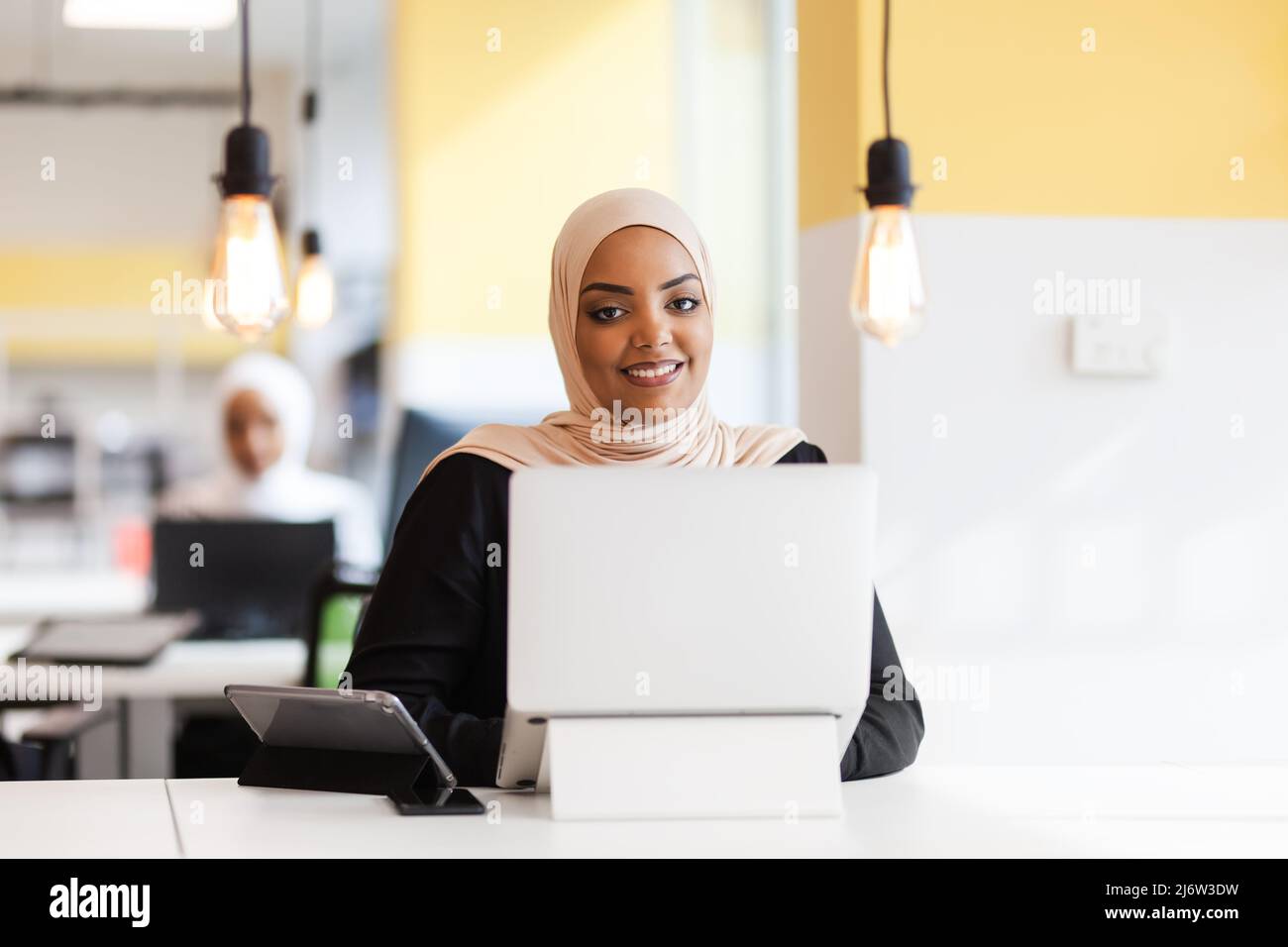 African american muslim girl with hijab working on a laptop in an ...