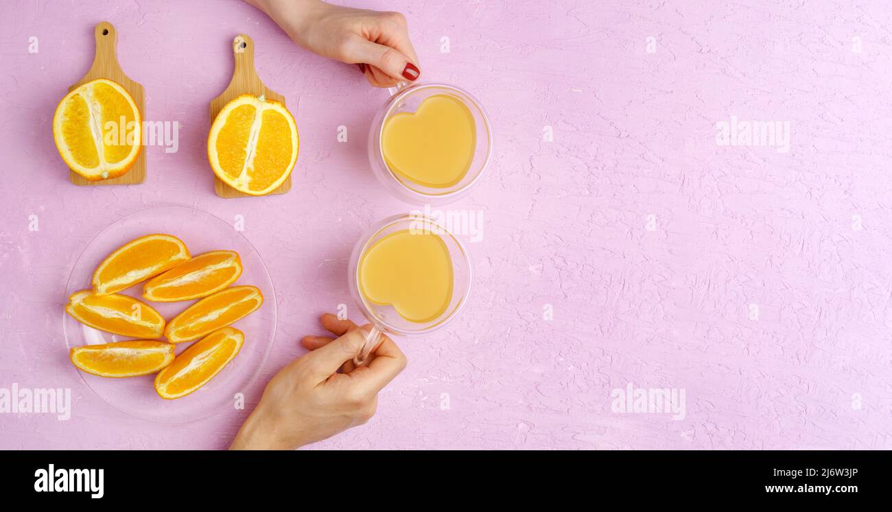 Fresh orange juice in glass and oranges on a pink colored background. Top view. Copy space Stock Photo