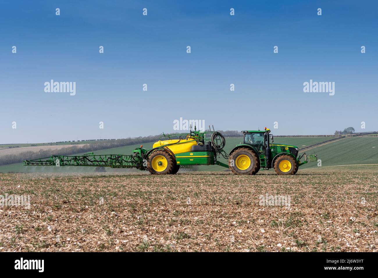 Spraying arable crop on the Yorkshire Wolds near York, using a John Deere 6215 tractor and a towed John Deere R952i sprayer. Stock Photo