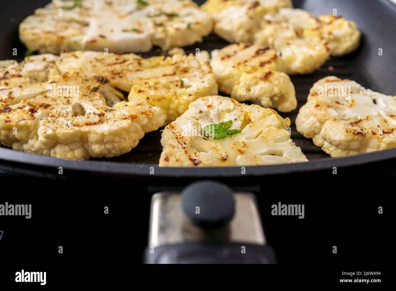 Cooking cauliflower steak with herbs and spices. Healthy vegetarian