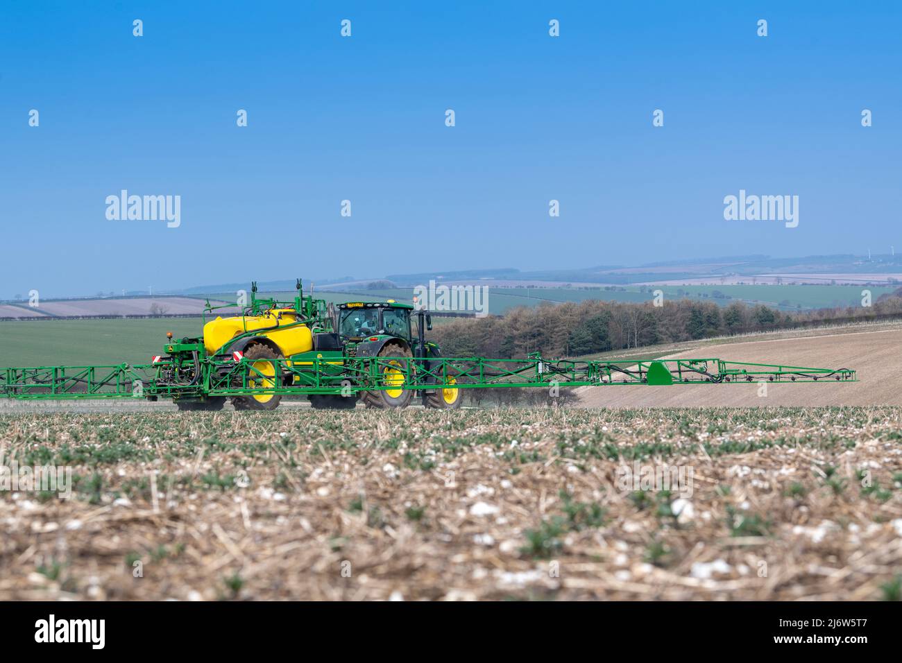 Spraying arable crop on the Yorkshire Wolds near York, using a John Deere 6215 tractor and a towed John Deere R952i sprayer. Stock Photo