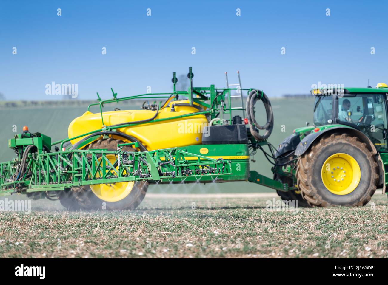 Spraying arable crop on the Yorkshire Wolds near York, using a John Deere 6215 tractor and a towed John Deere R952i sprayer. Stock Photo