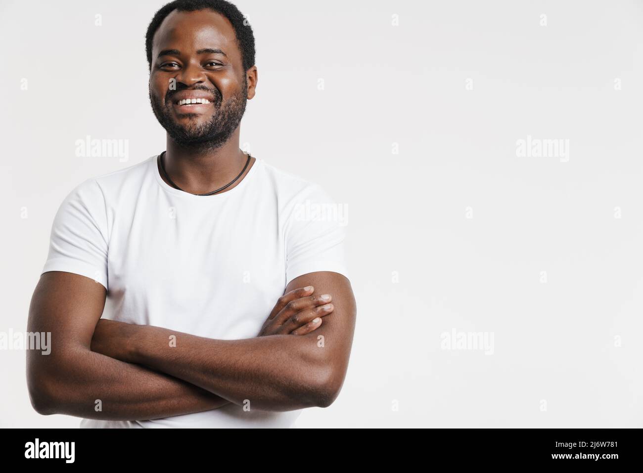 Black man laughing while posing with arms crossed isolated over white