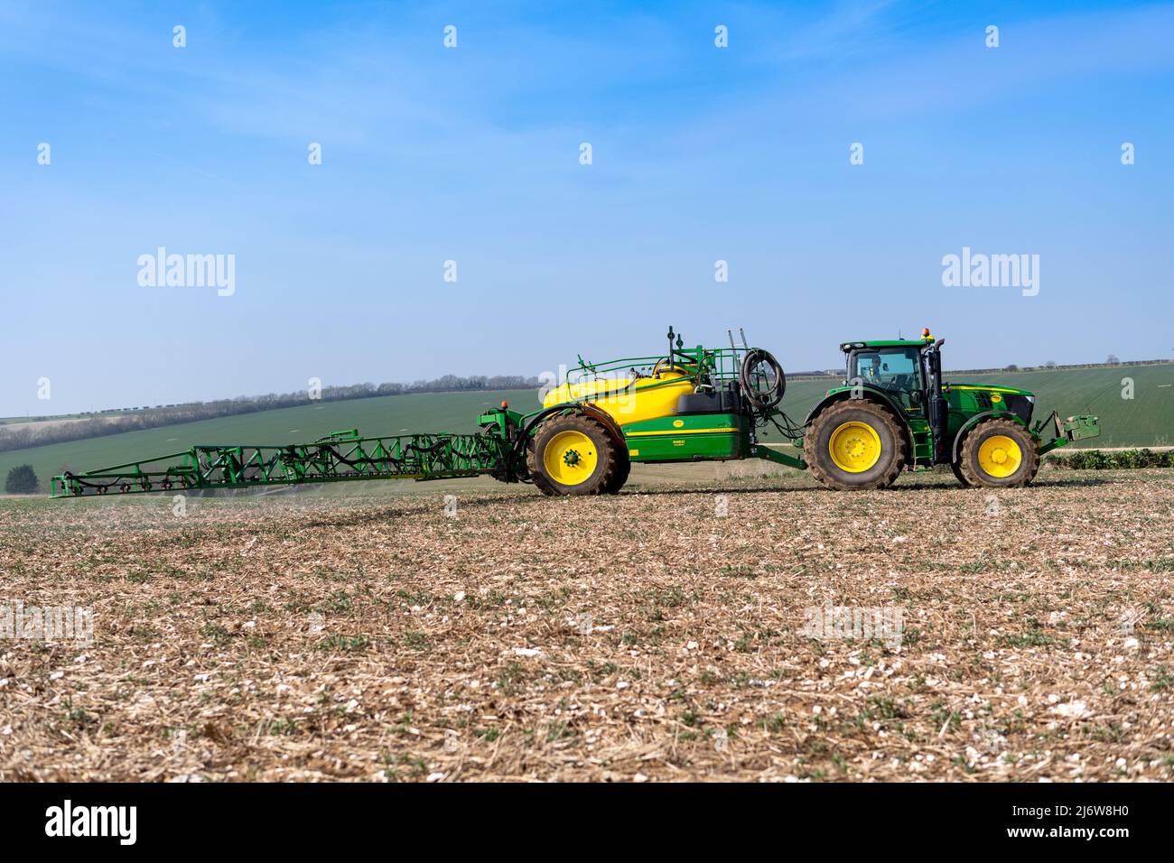 Spraying arable crop on the Yorkshire Wolds near York, using a John Deere 6215 tractor and a towed John Deere R952i sprayer. Stock Photo