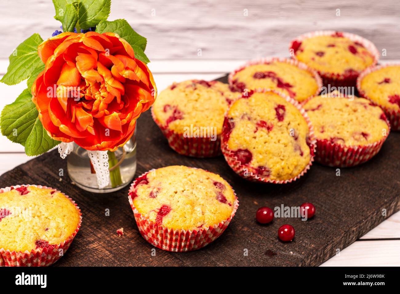 several currants muffins served on an old wooden board with bouquet of flowers Stock Photo