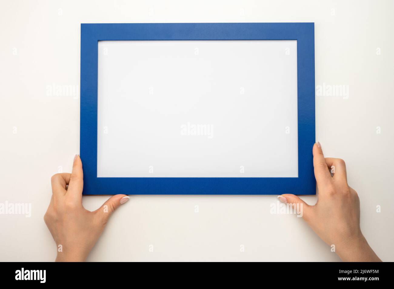Holding frame mockup. Photo Mockup. Woman hands hold blue frame. For frames and posters design. Frame size A4. isolated on white background. blank pho Stock Photo