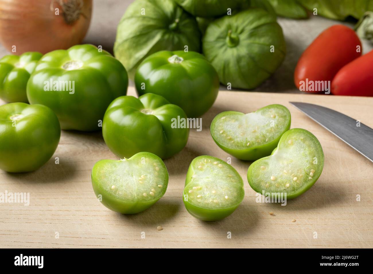 Fresh green whole and halved tomatillo on a cutting board close up Stock Photo