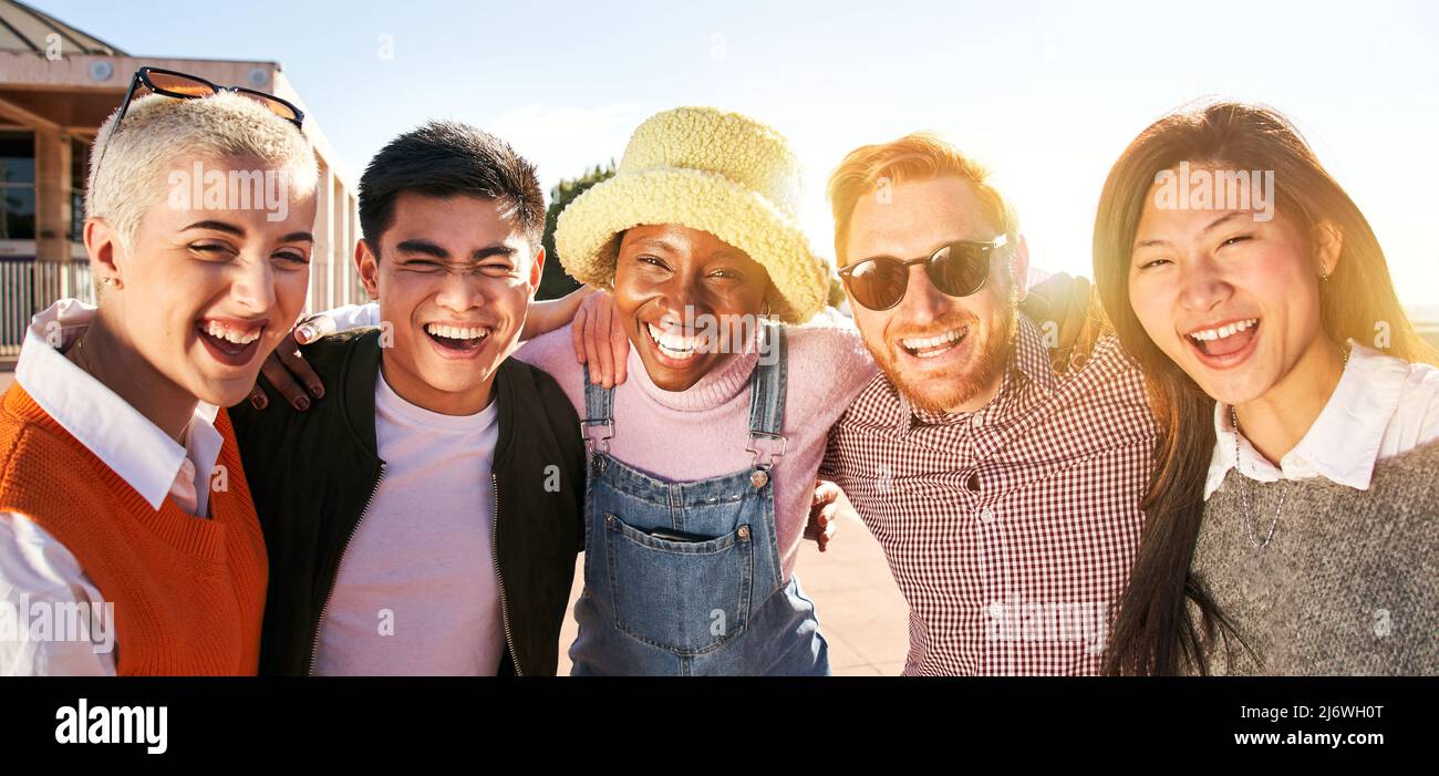 Smiling panoramic portrait of cheerful group of young people. Happy friends excited having fun. Interracial boys and girls taking picture looking at Stock Photo