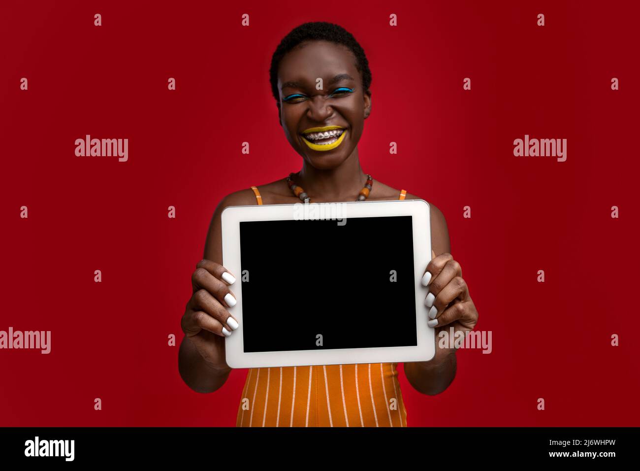 Happy stylish african american woman showing tablet with blank screen ...