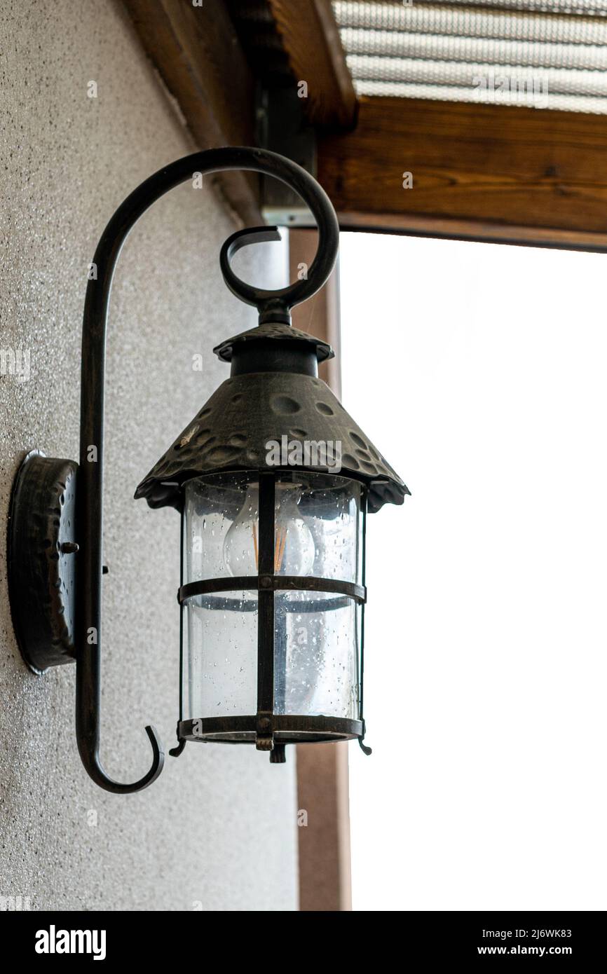 A black lamp is attached to the wall of the house from the outside ...