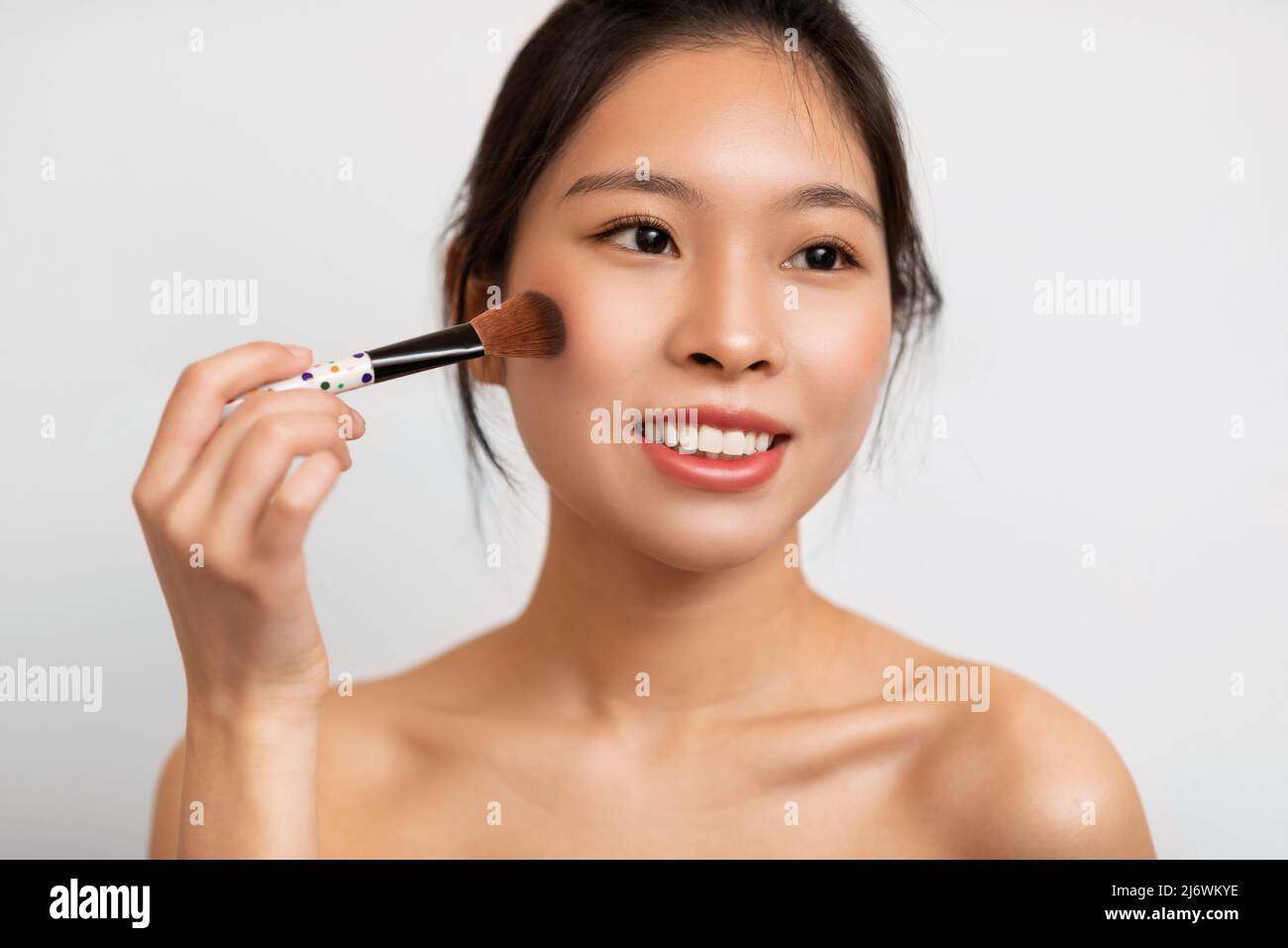 Portrait of beautiful Asian woman with makeup brush Stock Photo