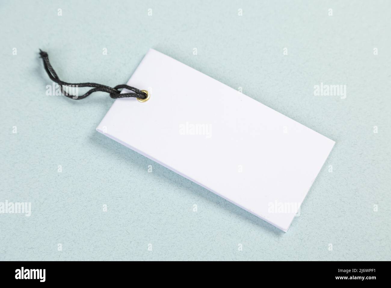 An empty white price tag lies on a gray-blue background with a soft shadow. Stock Photo