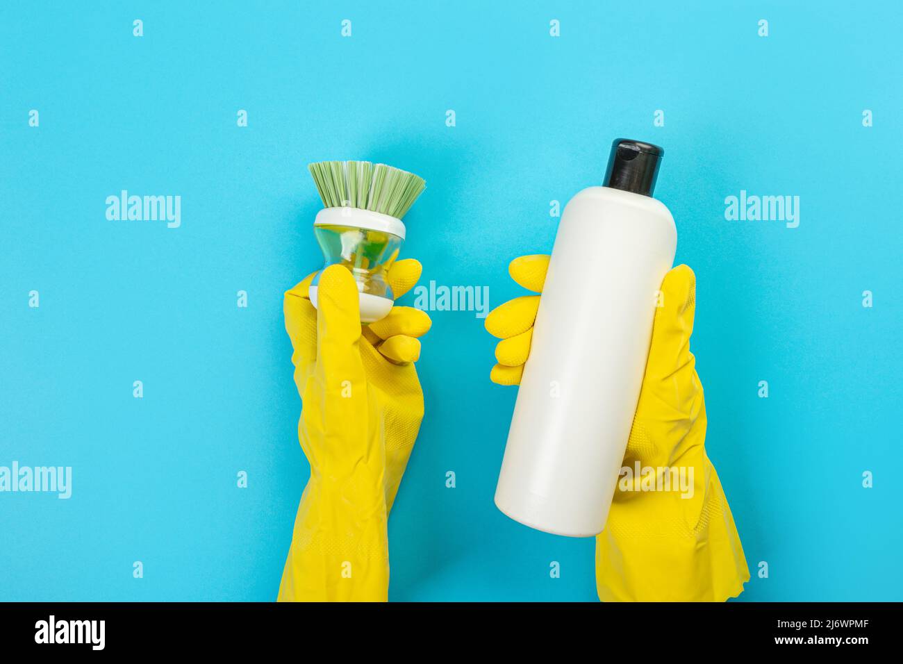 The hands of a housewife in yellow rubber protective gloves hold a ...