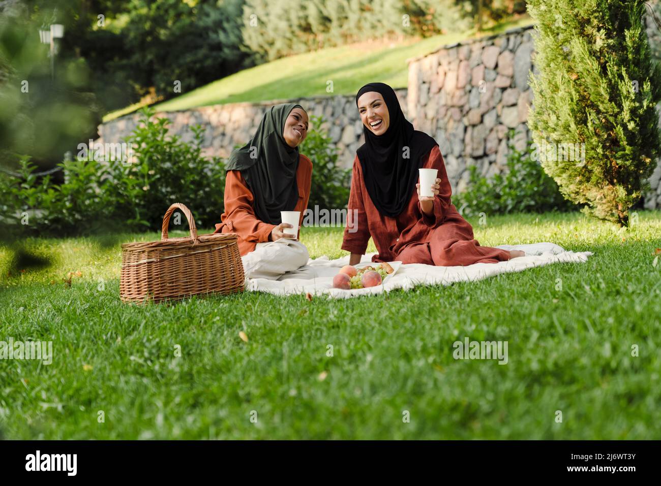 Multiracial muslim women laughing and talking during picnic in green park Stock Photo