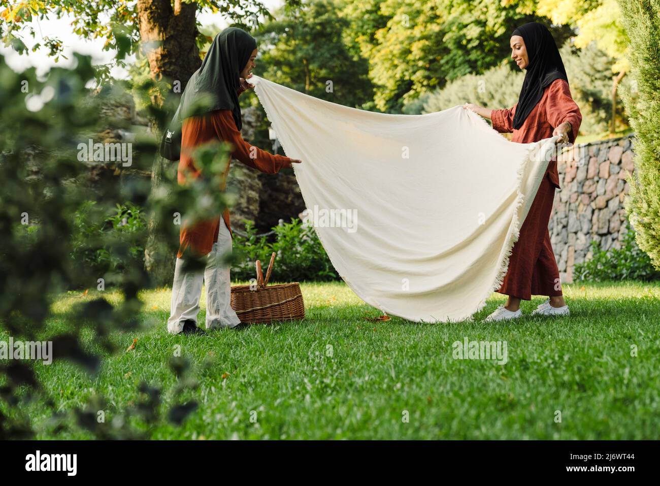 Multiracial muslim women making place for picnic in green park Stock Photo