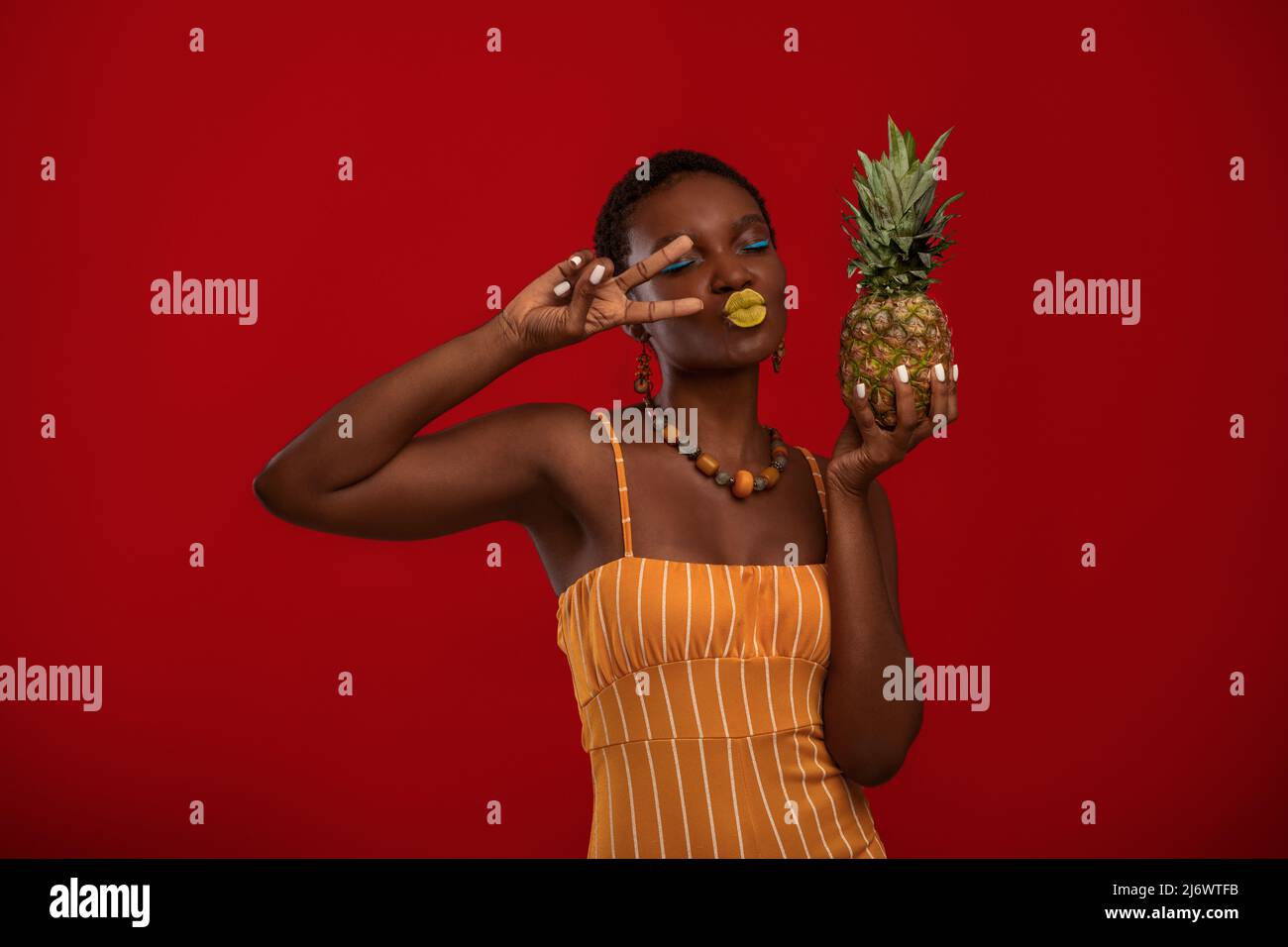 Emotional black lady fashionista with pineapple on red Stock Photo