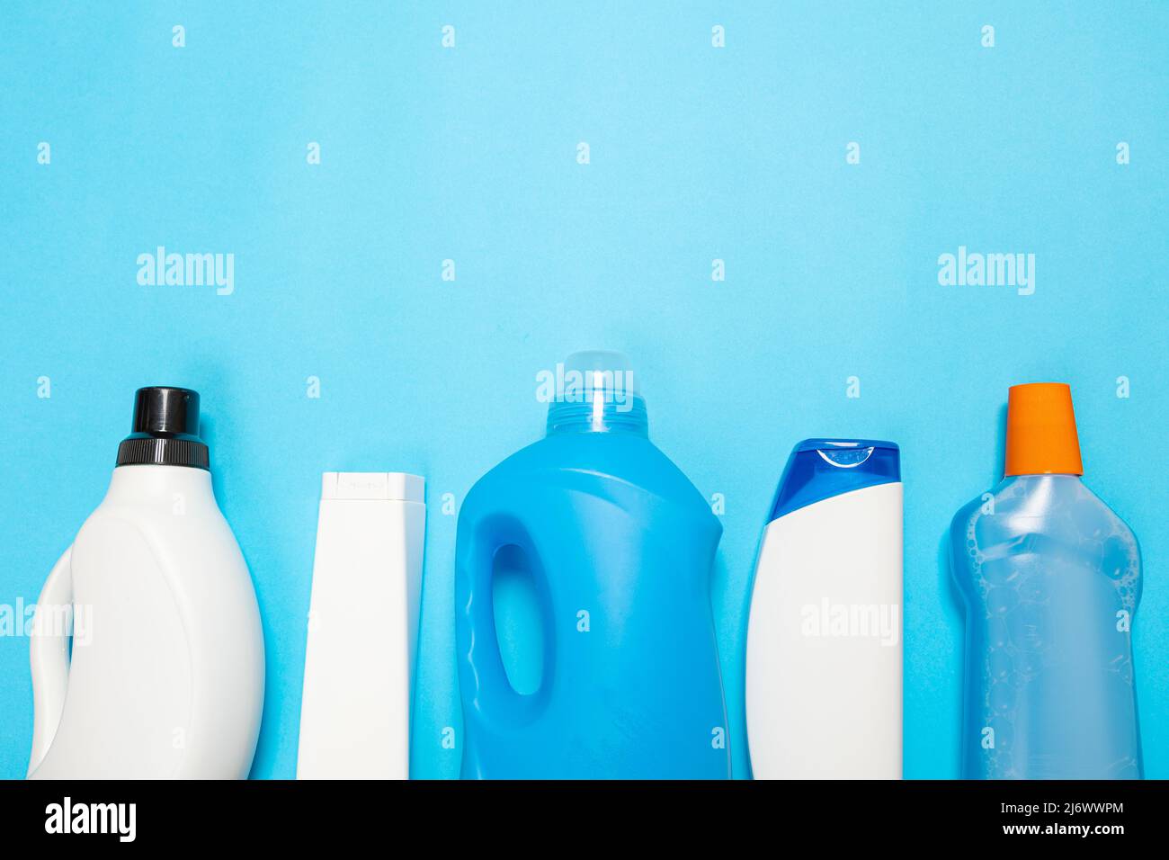 House cleaning supplies on blue background. Row of plastic bottles with