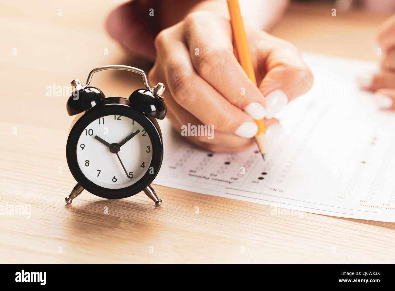 alarm clock with time running out. Students hands to take exams, write examination room with