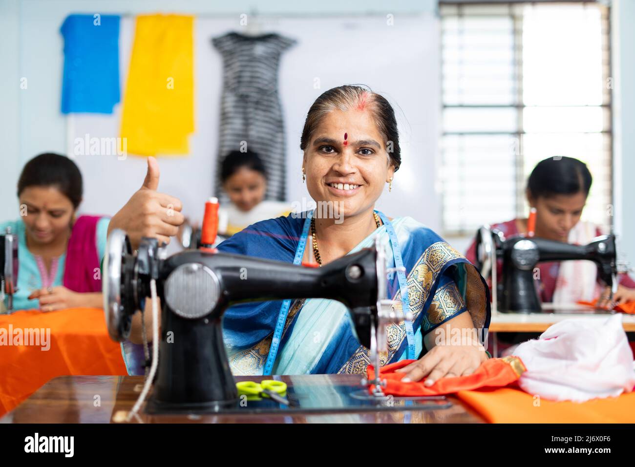 Happy smiling woman showing thumbs up sign by looking camera while