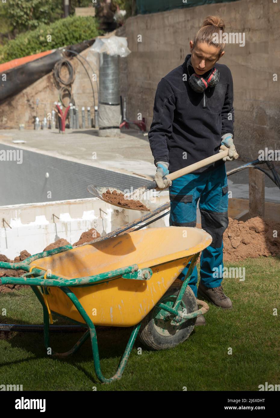 Young worker throwing soil inside a construction trolley with a shovel