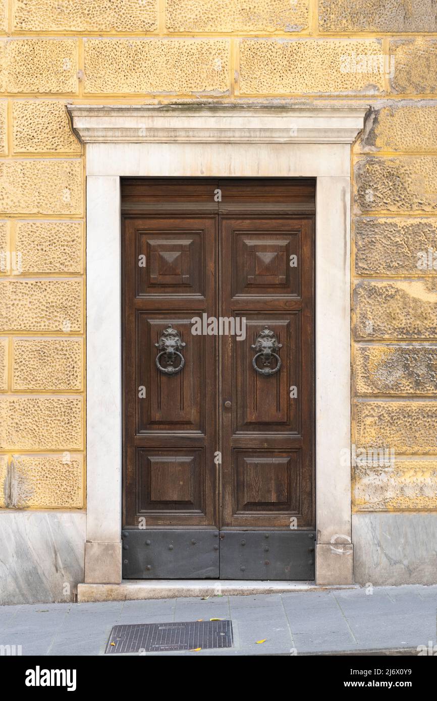 Ancient wooden door with Italian marble portal on a yellow renaissance building Stock Photo