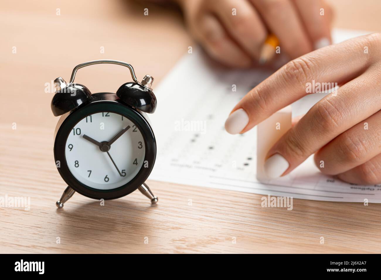 alarm clock with time running out. Students hands to take exams, write examination room with