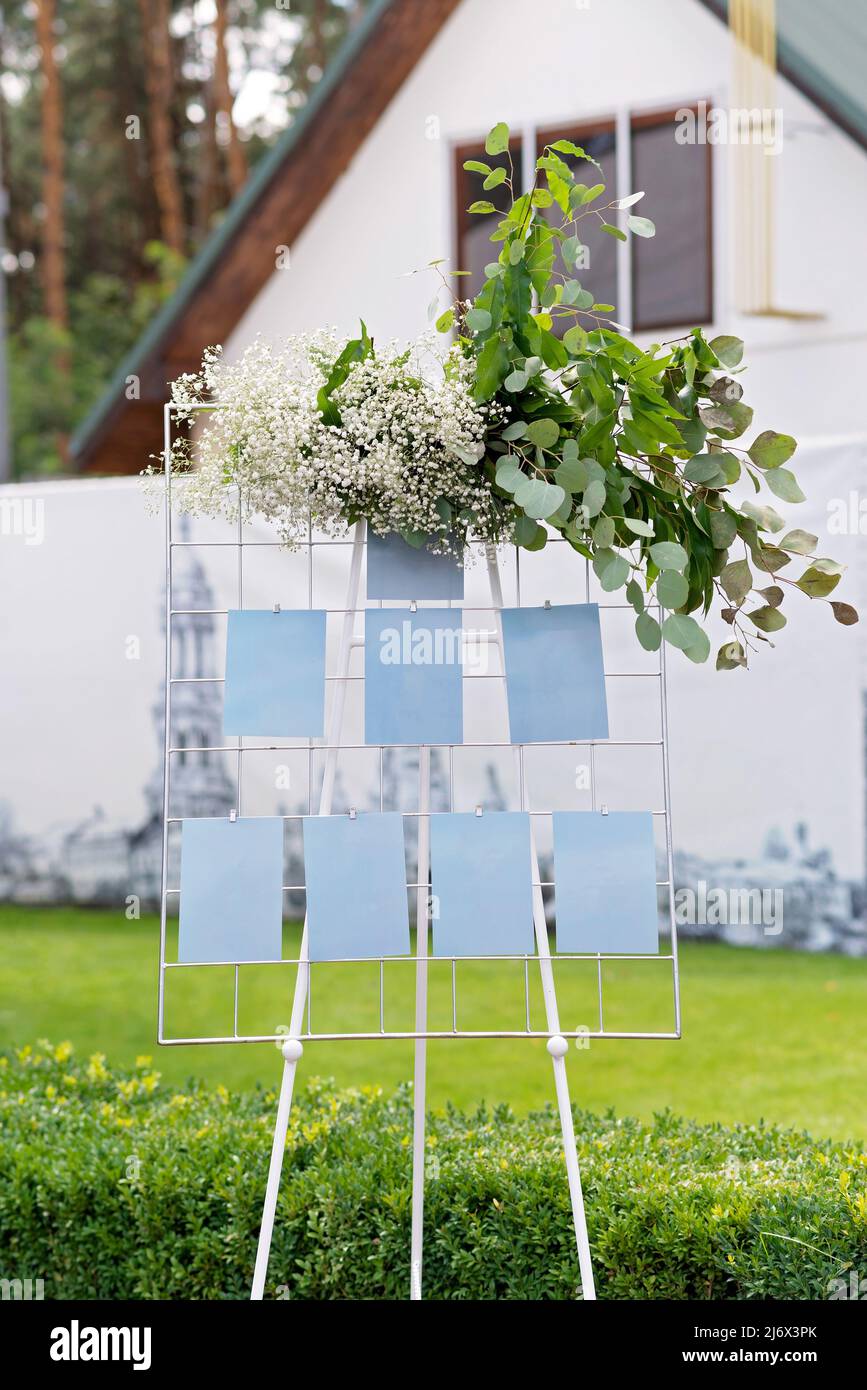 Wedding board, mockup, invitation easel, with space for an inscription, decorated with fresh flowers. Festive decor, copy space. Soft selective focus. Stock Photo