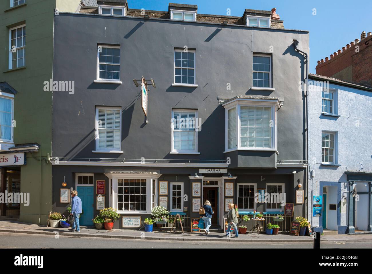Harbwr Brewery Tenby, view of people walking past the entrance to the Harbwr Brewery Tap & Kitchen in St Julian's Street in Tenby, Pembrokeshire Wales Stock Photo