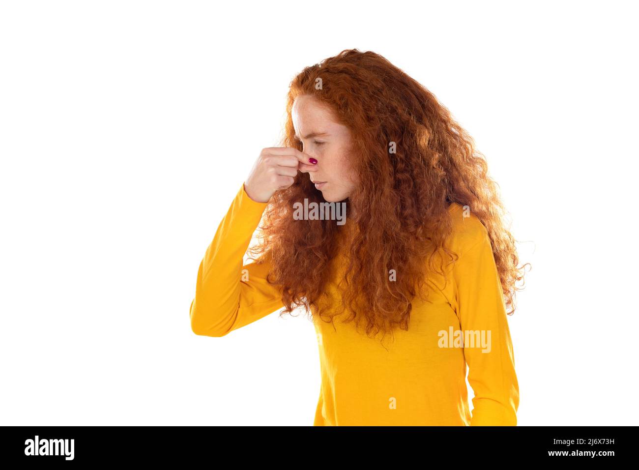 Beautiful fragile redheaded young woman in the dark. Sad frightened girl scared of abuse. Nonverbal behavior, body language. Red hair female looking s Stock Photo