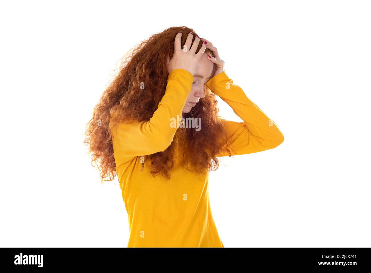 Beautiful fragile redheaded young woman in the dark. Sad frightened girl scared of abuse. Nonverbal behavior, body language. Red hair female looking s Stock Photo