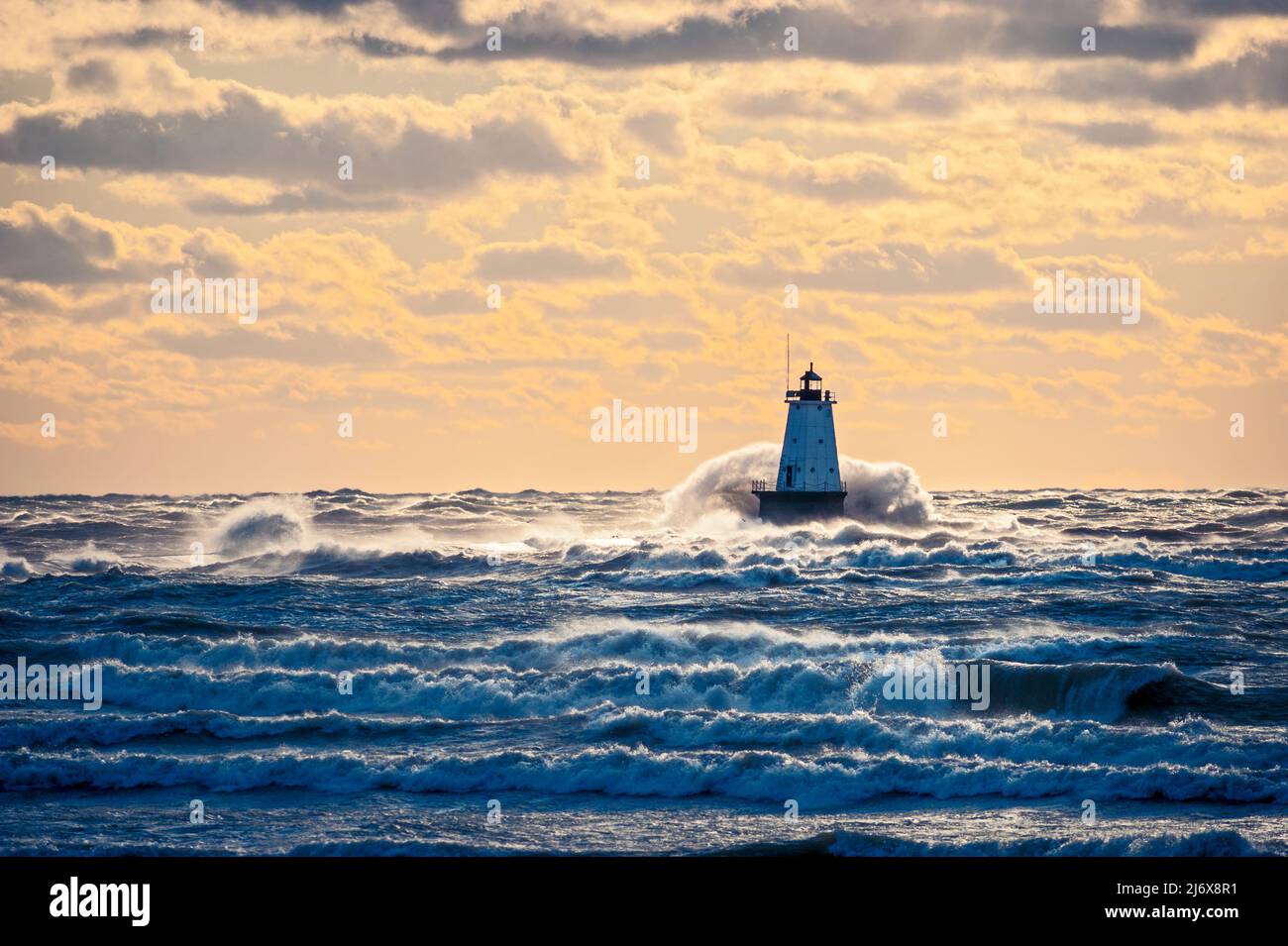 Big wave crashing over the north breakwall lighthouse at Streans Park in Ludington, Michigan, USA. Stock Photo