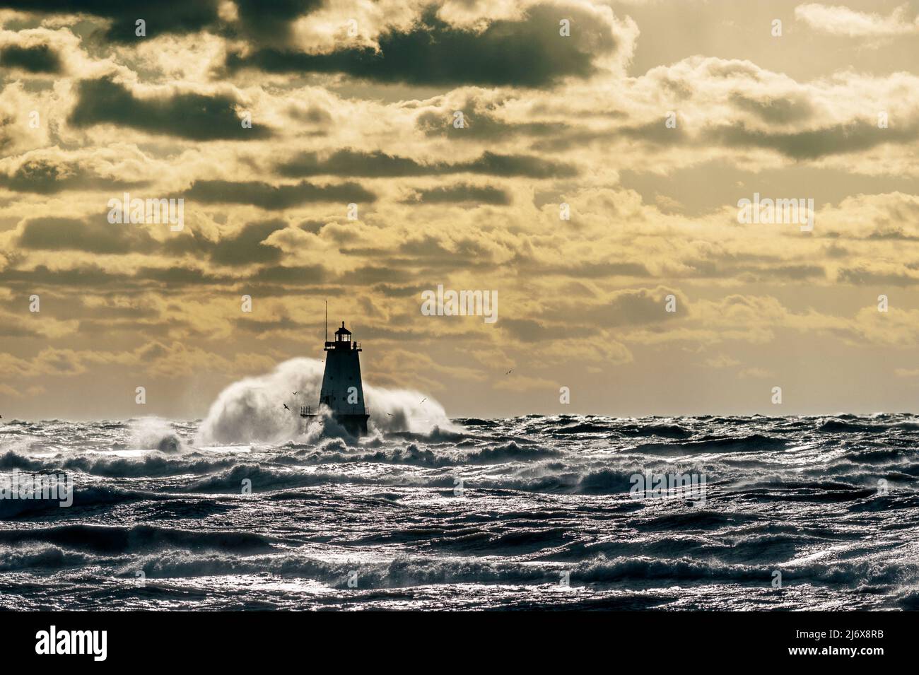 Big wave crashing over the north breakwall lighthouse at Streans Park in Ludington, Michigan, USA. Stock Photo