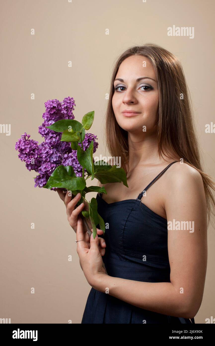 Beautiful young girl weared in black dress with a bouquet of lilac ...