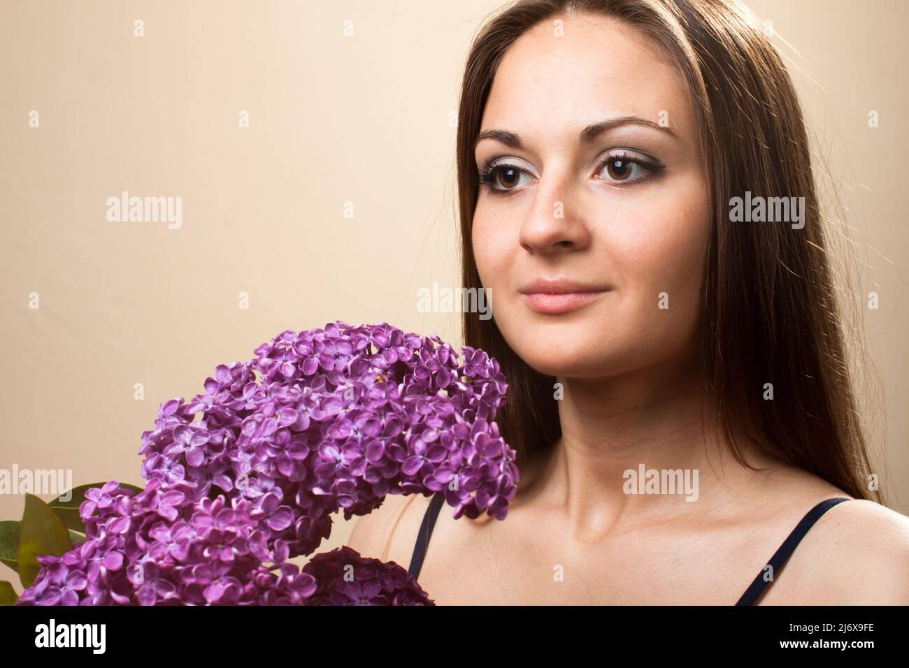 Beautiful young girl weared in black dress with a bouquet of lilac ...