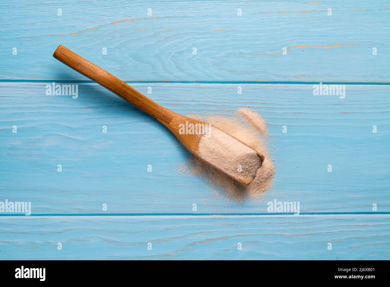 Collagen powder in spoon on wooden blue background. Stock Photo