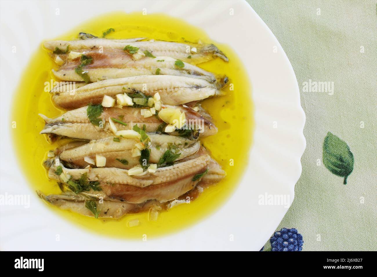 Cooked anchovy fish in vinegar with garlic, parsley and olive oil Spanish food. photo top view