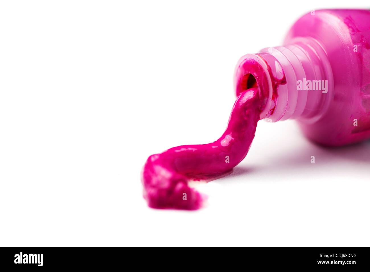 Close-up of an open tube of magenta artist paint spilling out on a white background. Stock Photo