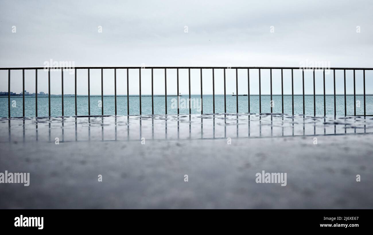 rainy day along Chicago lakefront focus on steel railing. view across the water with horizon in the distance Stock Photo