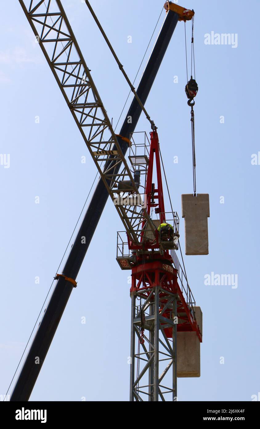 Mobile crane lifting a concrete counterweight into position for a tower