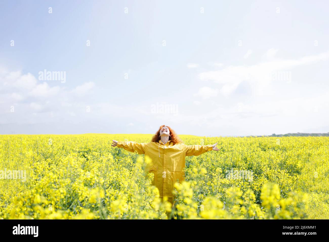 Grateful woman, being happy for a sunny summer day in a field of beautiful rapeseed flowers Stock Photo