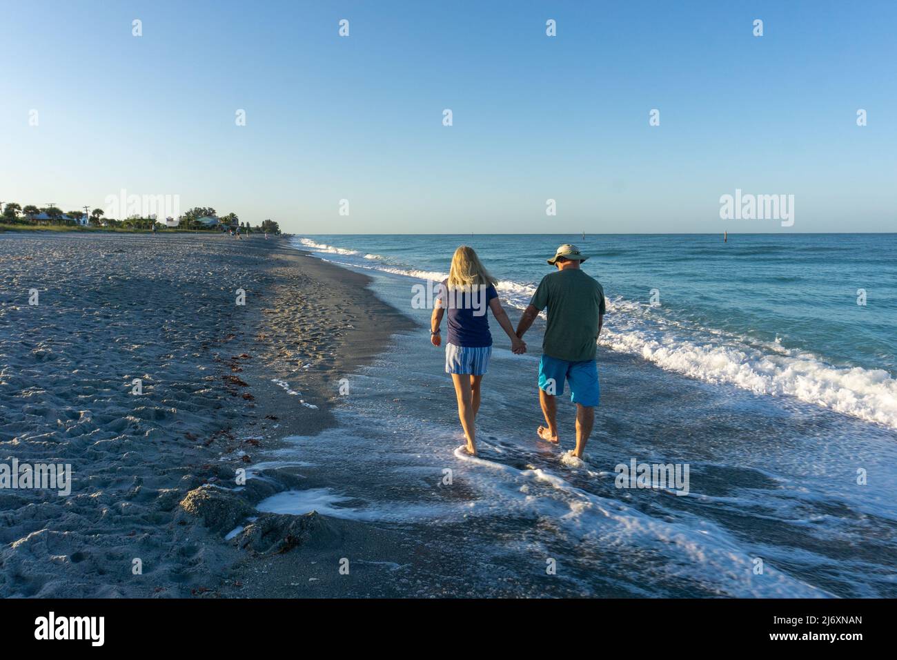 Old couple walking along beach in Florida Stock Photo