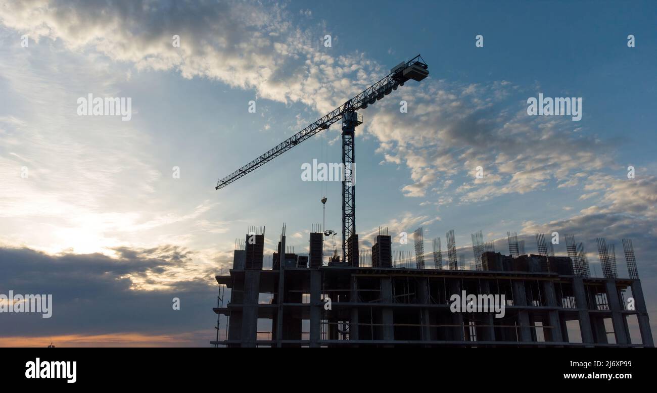 Construction site with cranes at orane yellow sunset. Working with installation metal. Download high quality photo Stock Photo
