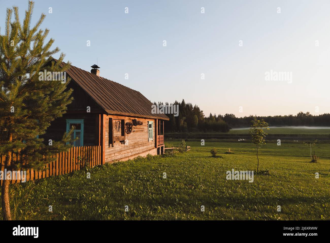 a wooden house in a picturesque countryside at sunset in summer Stock ...