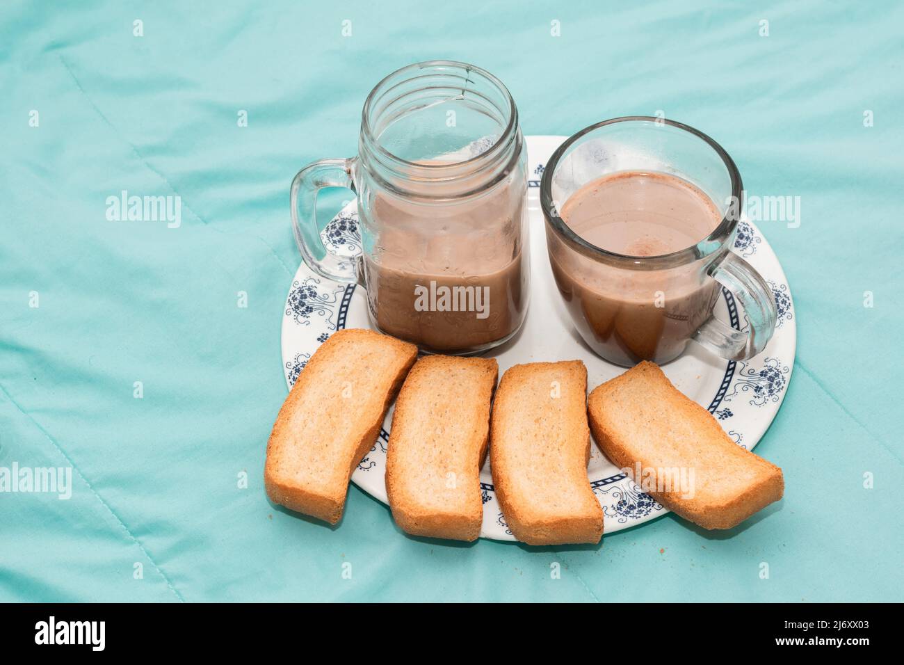 breakfast for two people served on a single plate with toast and two clear glass cups with chocolate on a light blue background. light snack for a cou Stock Photo
