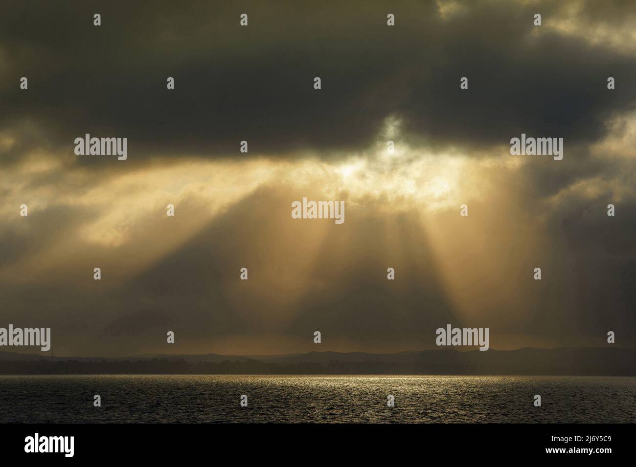 Sunrays shining through stormy sky over water. Lake Macquarie, New South Wales, Australia Stock Photo