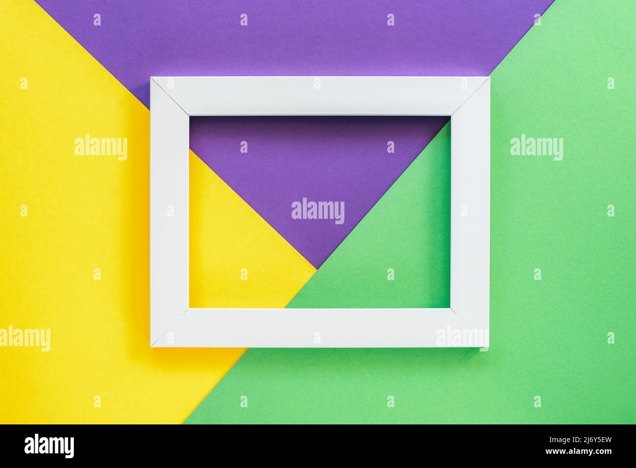 Three toned green, yellow and purple background with blank picture frame. Top view, flat lay. Stock Photo