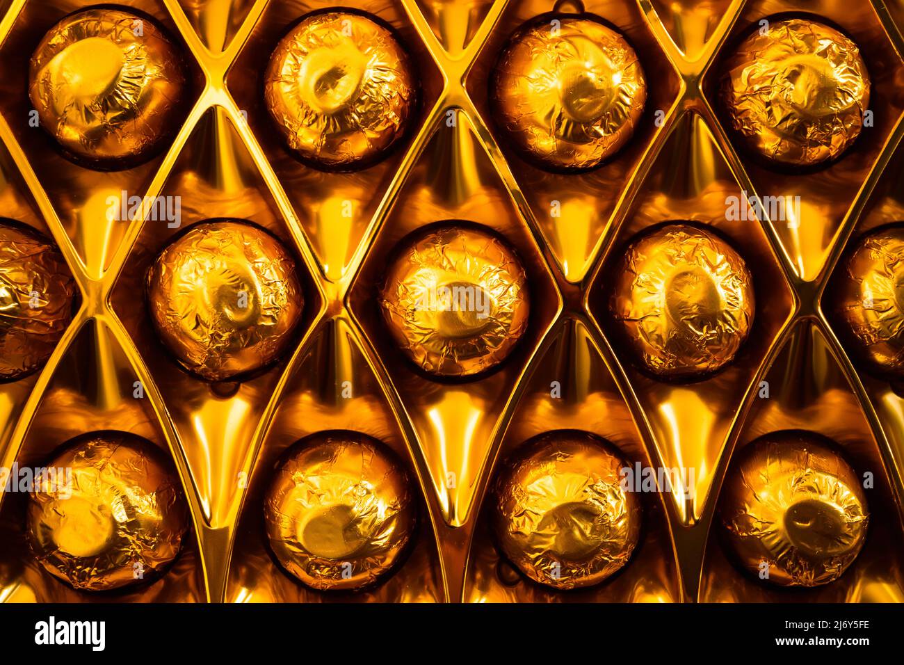 Close up of chocolate bonbons wrapped in gold foil in their box Stock Photo