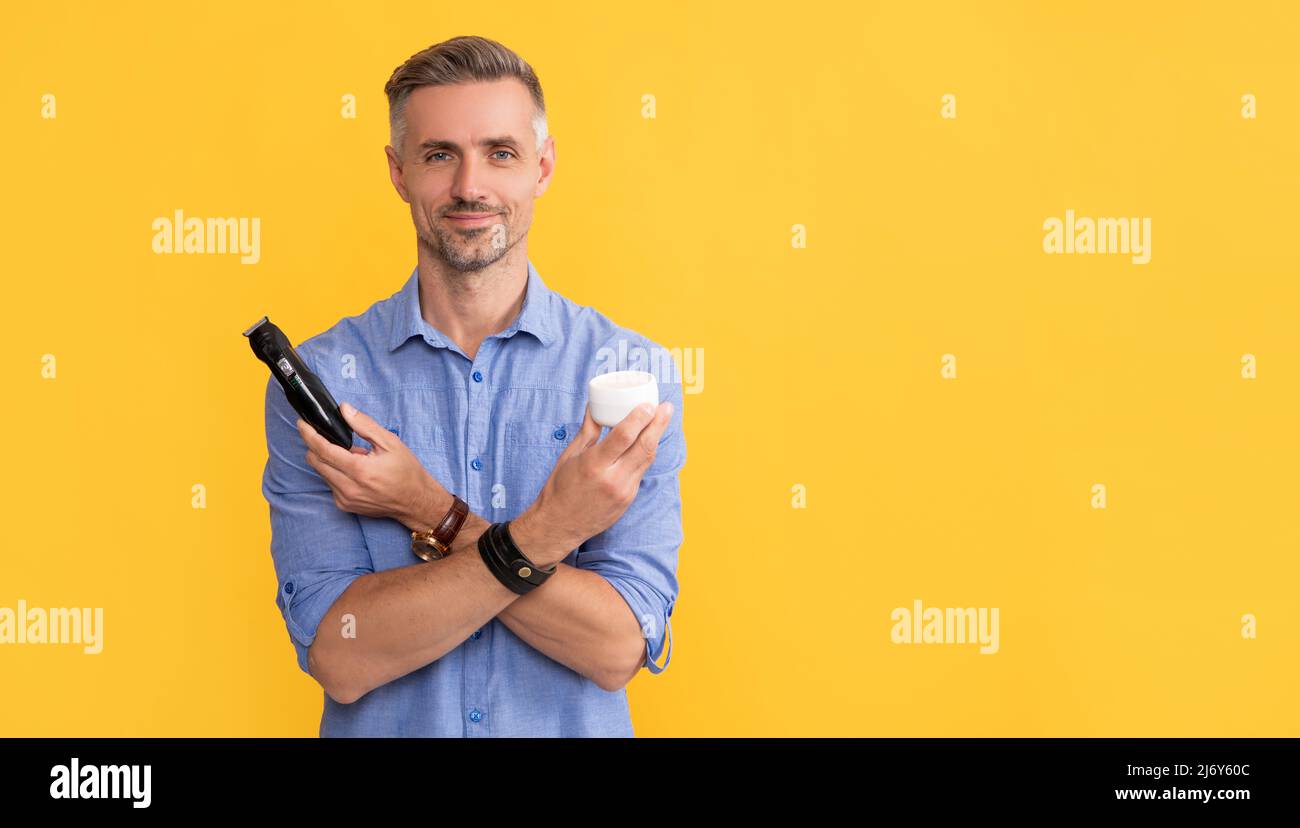 after shave. man holding electric shaver and cream. grizzled guy presenting electric razor Stock