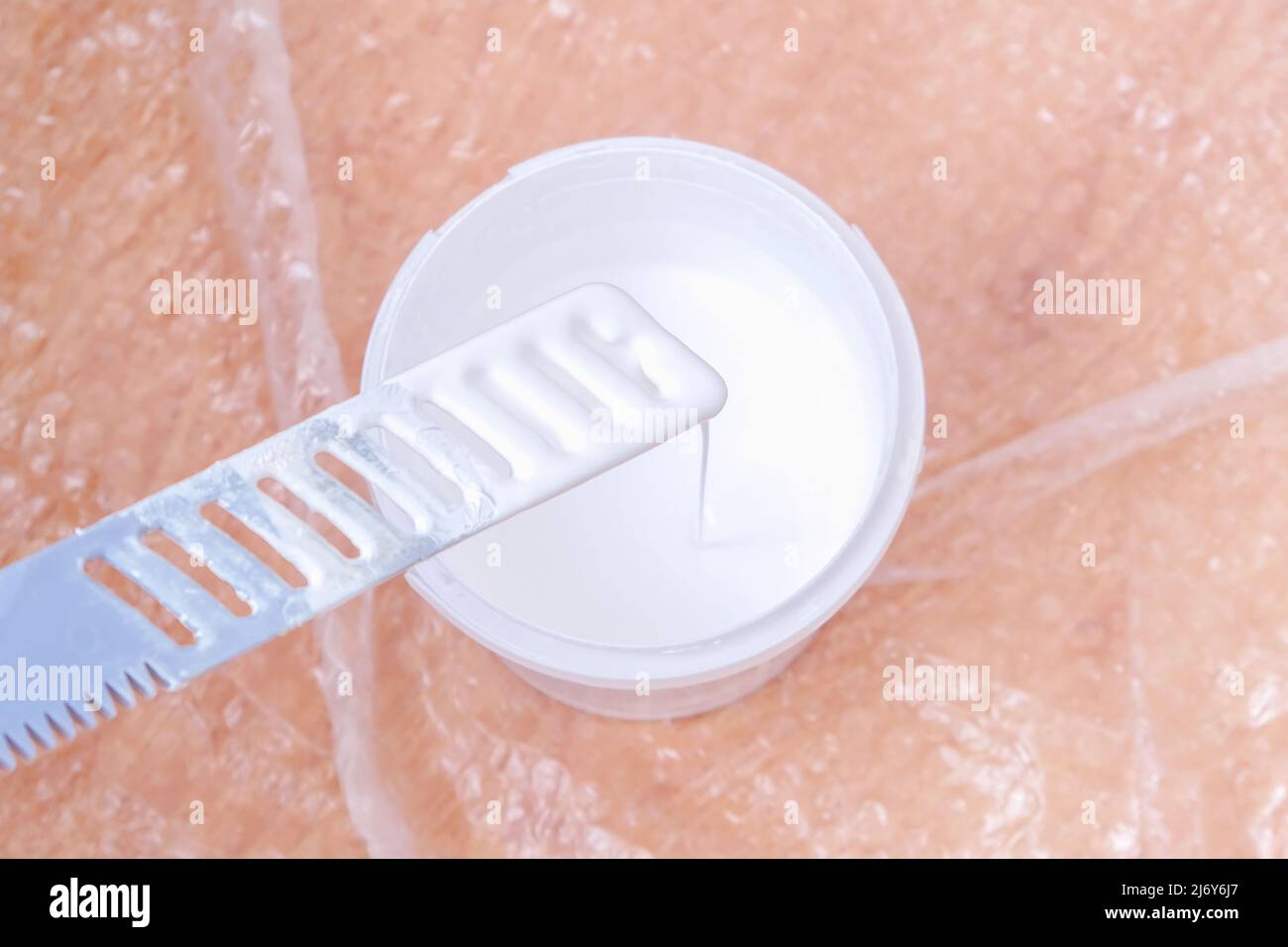 A man stirs white acrylic paint with a special plastic stirrer