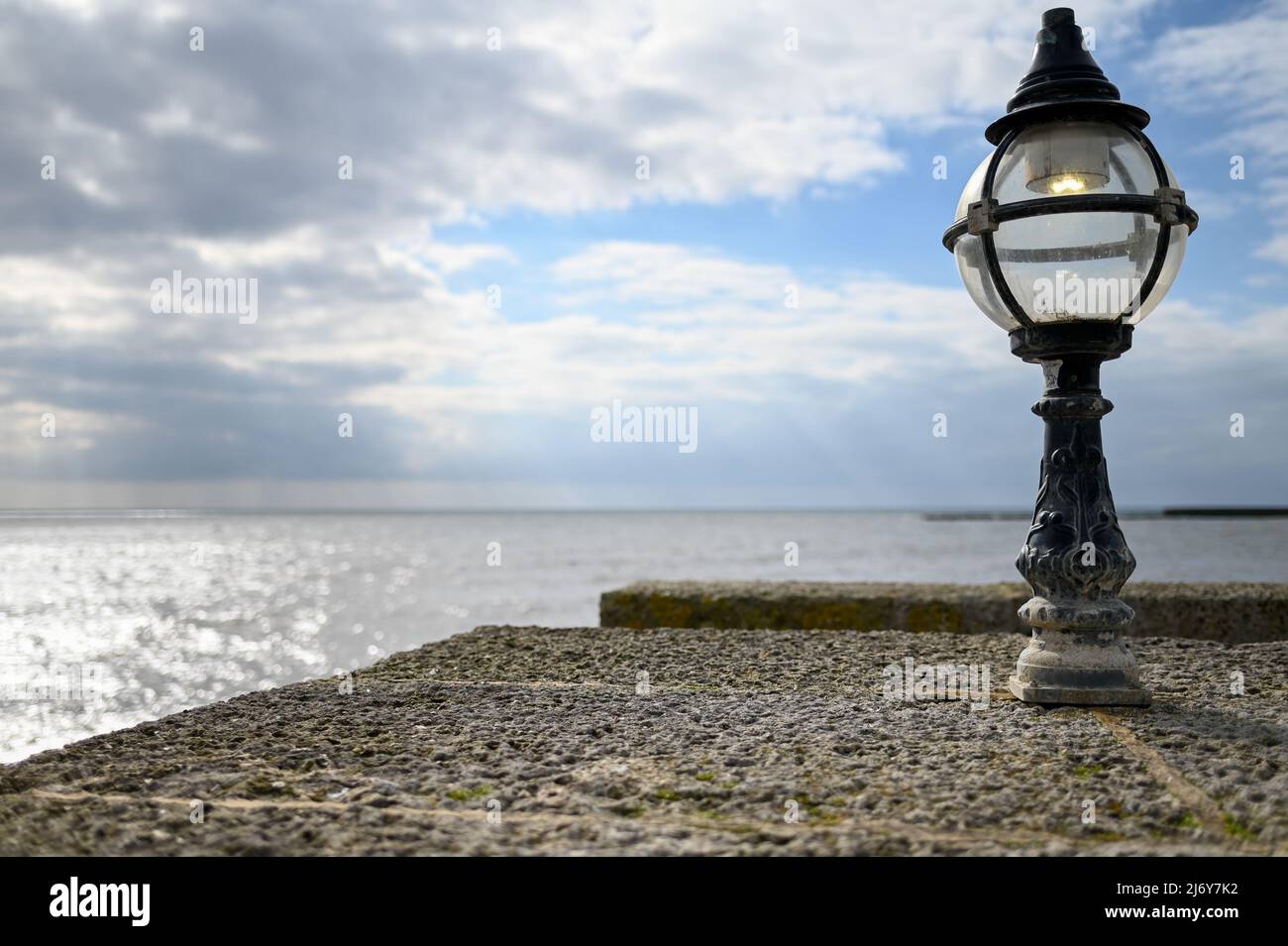 Ocean view at Lyme Regis from stone wall with Lamp in foreground Stock Photo